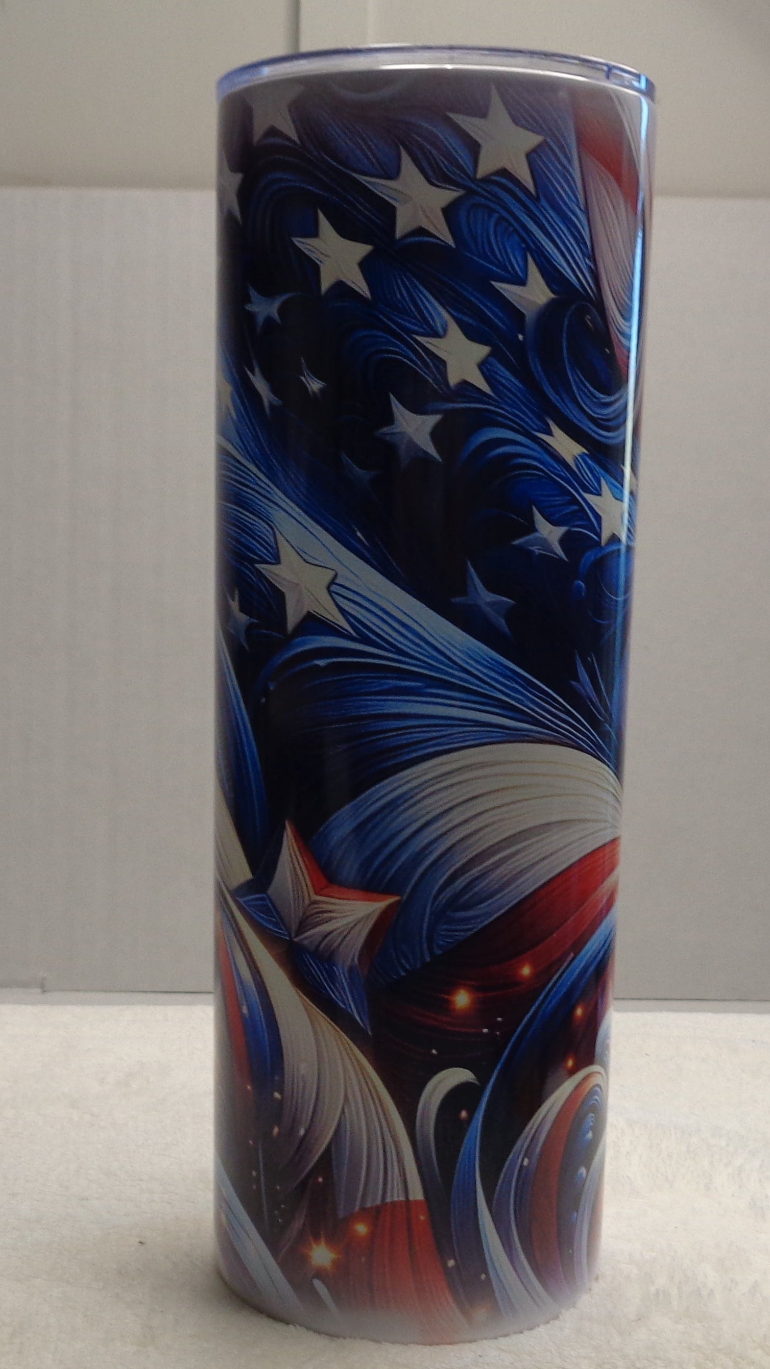 20 oz tumbler with a patriotic American flag design, featuring blue and white stars and red, white, and blue abstract swirls. 