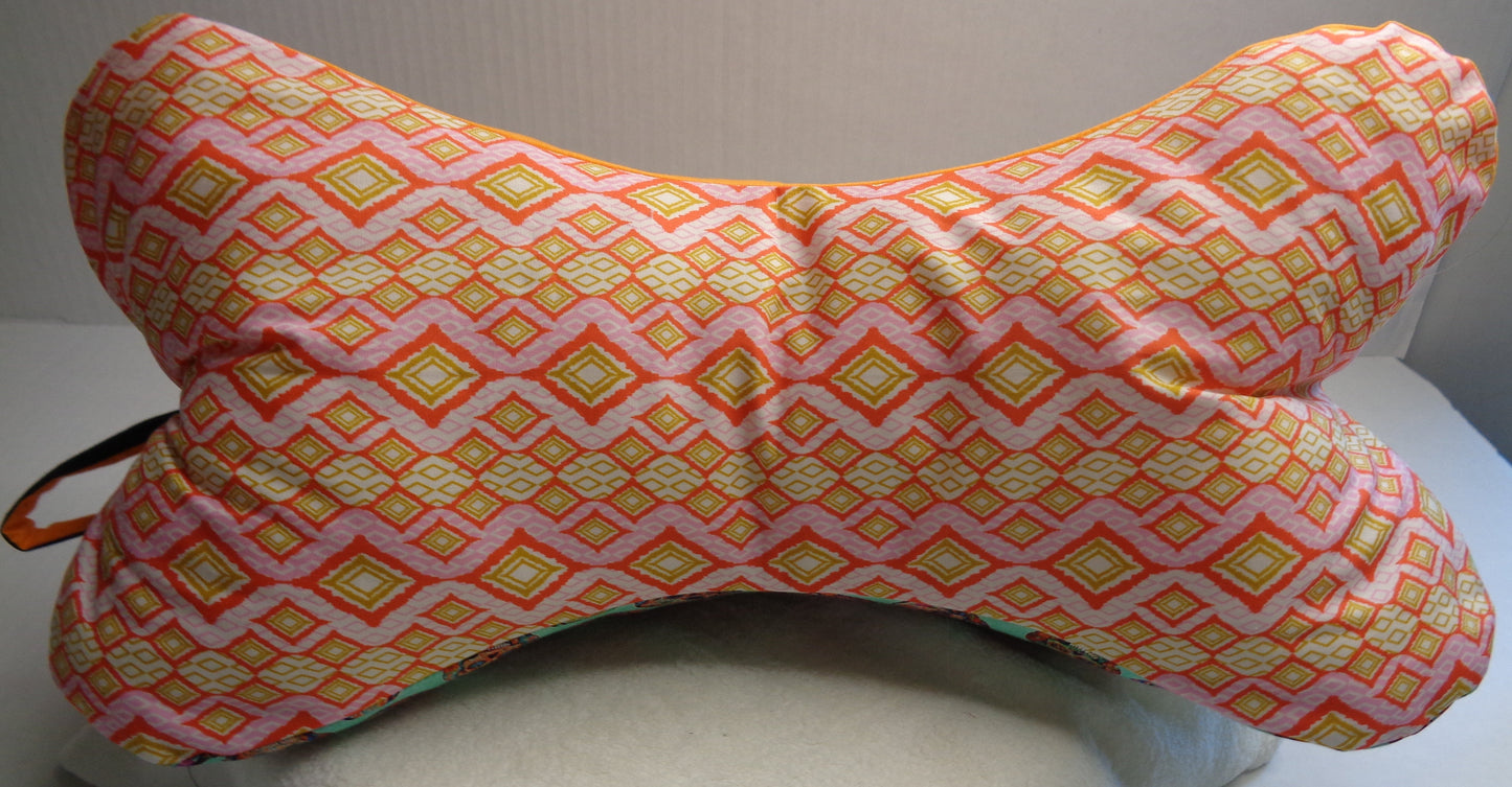 A bone-shaped neck pillow with a pink, orange, and yellow geometric diamond pattern. 
